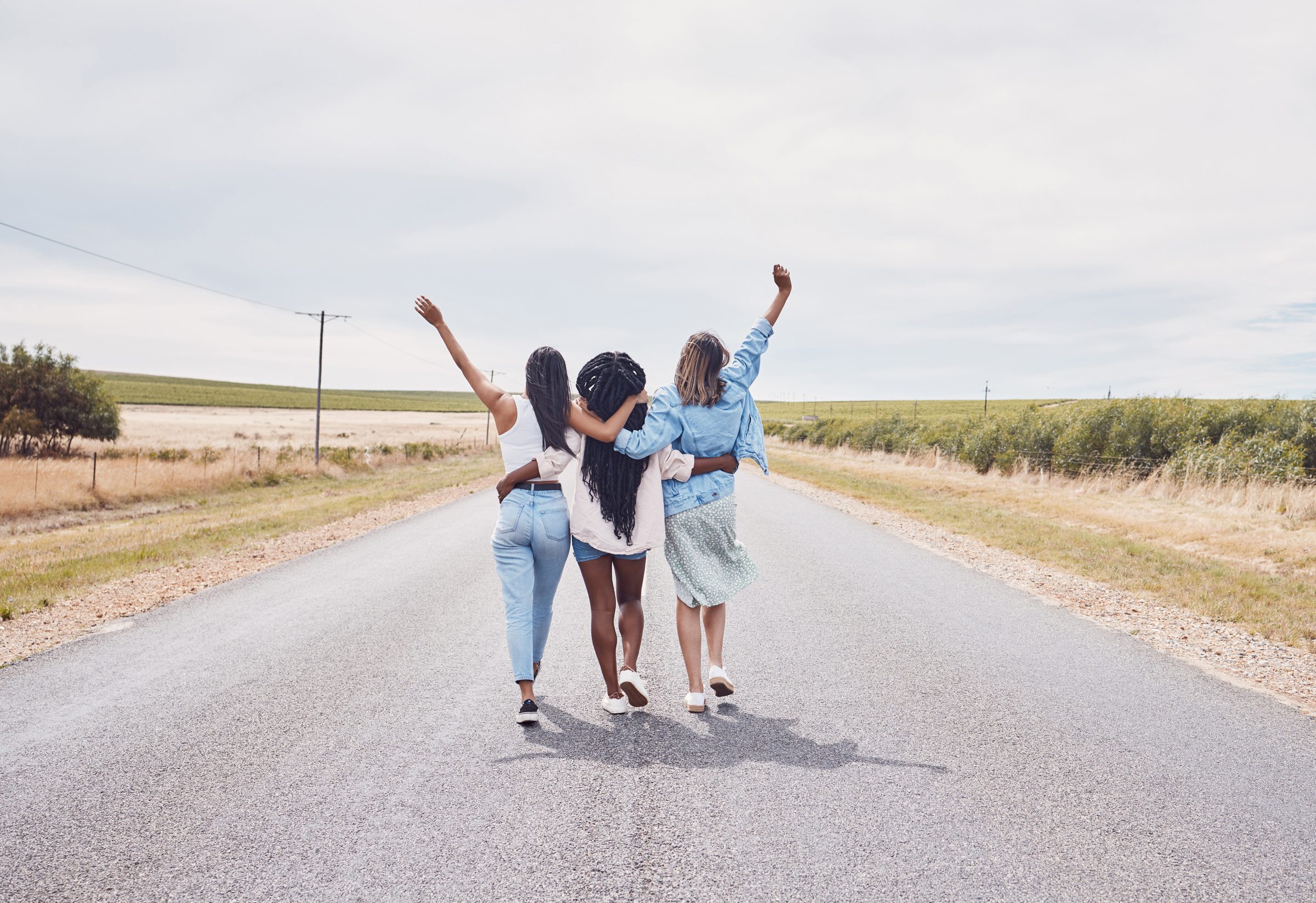 Three women walking together down an open road